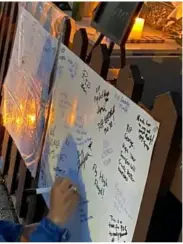  ??  ?? FAR LEFT: Members of the public sign a tirbute board outside Cathy’s home.