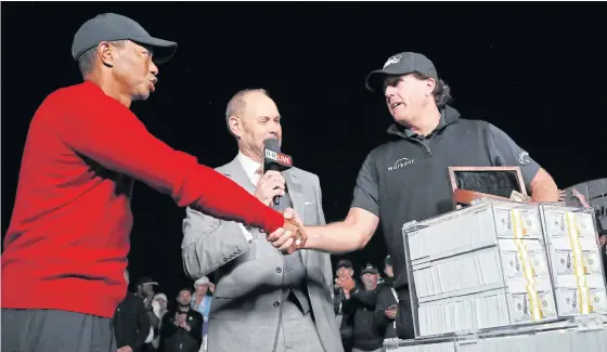  ??  ?? Phil Mickelson, right, shakes hands with Tiger Woods after winning their exhibition match and US$9 million in prize money.