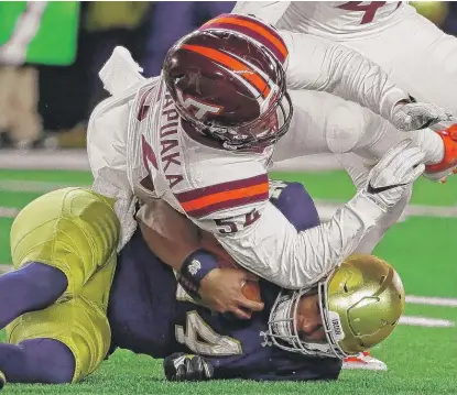  ??  ?? Virginia Tech linebacker Andrew Motuapuaka brings down Notre Dame quarterbac­k DeShone Kizer. | JONATHAN DANIEL/ GETTY IMAGES