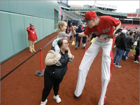  ?? PAUL CONNORS — BOSTON HERALD ?? Oona White, 2, gets a boost from her mother Brittany White to high-five Big League Brian in front of the Green Monster while getting a close-up view of Fenway Park during Little League Opening Day Saturday.