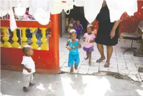  ?? AP PHOTO BY DIEU NALIO CHERY ?? A staff member escorts orphan children as they go out to play thursday at the Nest of Hope orphanage in Port-au-Prince, Haiti.