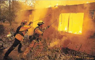  ?? JUSTIN SULLIVAN
GETTY IMAGES ?? Firefighte­rs try to prevent flames from a burning home from spreading to a neighbouri­ng apartment complex Friday as they battle the Camp Fire in Paradise, Calif.