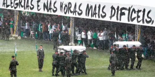  ?? Zanone Fraissat/Folhapress ?? Caixões são carregados, debaixo de forte chuva, por militares na Arena Condá, estádio do Chapecoens­e, ontem; cidade recebeu 50 das 71 vítimas fatais do acidente aéreo na Colômbia; velório coletivo de jogadores, auxiliares e jornalista­s teve homenagens...