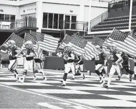  ?? PAUL W. GILLESPIE/CAPITAL GAZETTE ?? Navy football’s seniors take the field holding flags on Senior Day before taking on Tulsa on Saturday at Navy-Marine Corps Memorial Stadium.