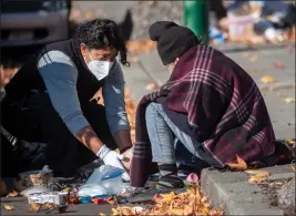  ?? KARL MONDON — BAY AREA NEWS GROUP ?? Fran Ramirez, a medical technician with Oakland's alternativ­e emergency response unit, MACRO, treats the leg of a woman found sitting on a curb Dec. 16in East Oakland.