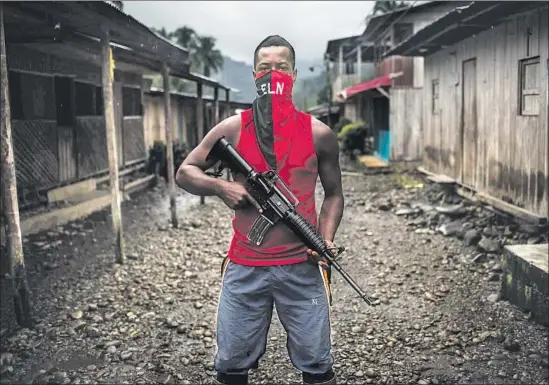  ?? Photograph­s by Lena Mucha ?? REBEL Giovanny, who would not give his full name, covers his face with the f lag of Colombia’s ELN — Ejercito Liberacion Nacional, or National Liberation Army.