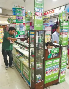  ?? SUNSTAR FOTO ?? LONGER SHELF LIFE. A customer (left) buys prepaid load from a kiosk in a downtown mall in Cebu City. A new memorandum circular has ordered the extension of the expiry of prepaid load credits.