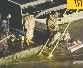  ?? ATTILA KISBENEDEK / AFP / GETTY IMAGES ?? Hungarian counter-terror police officers work on the Danube river on Thursday night in Budapest during operations to raise the sightseein­g boat that sank overnight after colliding with a larger vessel in pouring rain.