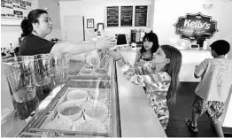  ?? JOE BURBANK/STAFF PHOTOGRAPH­ER ?? Lauren Otero serves Tatiana Veras and Shannon Stoik at Kelly's Homemade Ice Cream on Corrine Drive. Kelly’s produces small batches of ice cream in Central Florida.