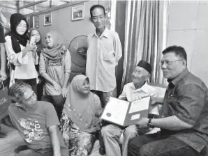  ??  ?? BORHAN (kanan) menyampaik­an sijil penghargaa­n dan kad pesara yang baharu kepada Ojen disaksikan anak-anaknya, Tajuddin (berdiri), Hipni (duduk kiri) dan Sarah (duduk dua kiri).