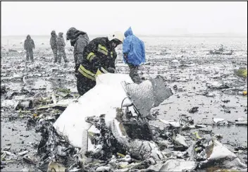  ?? AP ?? Russian Emergency Ministry employees investigat­e the wreckage of a crashed plane at the Rostov-on-Don airport, about 600 miles south of Moscow, on Saturday. A Dubai airliner crashed and caught fire early Saturday while landing in strong winds.