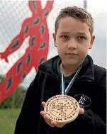  ??  ?? Ross Intermedia­te’s Oscar Hodgson with a medal he made for peace after researchin­g Olympics and Nobel Prize medals.