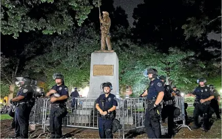  ?? PHOTO: REUTERS ?? Police wearing riot gear guard a statue of a Confederat­e soldier nicknamed Silent Sam on the campus of the University of North Carolina in Chapel Hill yesterday during a demonstrat­ion calling for its removal.