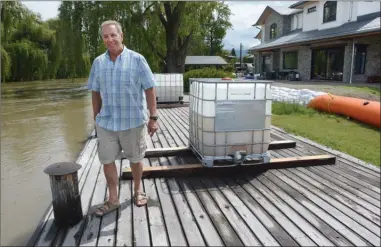  ?? GARY NYLANDER/The Daily Courier ?? Georg Schurian, whose house is located at the end of Bluebird Road, looks over Mission Creek as it spills into Okanagan Lake on Wednesday. Plastic bins filled with water rest on his dock to hold it in place in case of flooding.