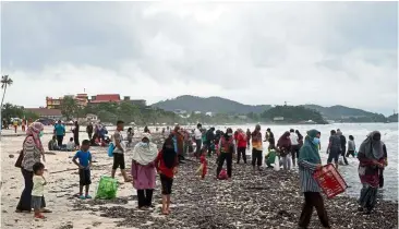  ??  ?? Seashells by the seashore: A crowd with baskets and plastic bags in hand collecting the shellfish on the beach in Langkawi. — Bernama