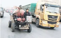  ??  ?? A worker drives a motorised vehicle past trucks parked outside ceramics factories in rural Gaoyi county near Shijiazhua­ng, Hebei province, China.After a decade of developmen­t, often through buying or benchmarki­ng foreign technology and know-how,...