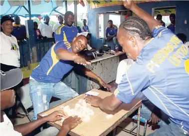  ?? ANTHONY MINOTT ?? Passagefor­t United’s pair of Anthony Simpson ( background) and Garnet Duffus, slam the table while winning a game over their Ken’s Wildflower opponents during their Colin Fagan- sponsored South East St Catherine Constituen­cy Domino League quarter-...