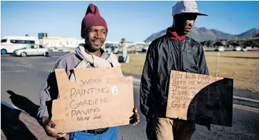  ?? NIC BOTHMA EPA ?? TWO unemployed men hold self-made advertisin­g boards offering their services at a traffic intersecti­on in Cape Town. |