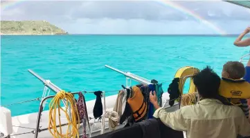  ??  ?? Mark Thompson watches a rainbow arc over Great Camanoe Island after a morning rain squall has passed.