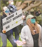  ?? (AP/Gregory Bull) ?? Employees of Vi at La Jolla retirement complex hold signs and wave flags for the residents during an afternoon pep rally April 8 in San Diego. As elderly residents who have been quarantine­d for weeks make their way out onto their balconies, employees below dance, wave flags and shout words of encouragem­ent in a now almost daily afternoon pep rally.