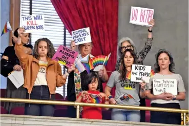  ?? AP PHOTO/MARK ZALESKI ?? On Monday during a legislativ­e session in Nashville, protesters hold signs in the House gallery against the bill by Rep. Mary Littleton, R-Dickson, that would require parents to be notified of a student’s intention to transition to a gender different from birth.