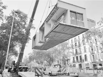  ??  ?? A prefabrica­ted apartment is set up on a building’s roof by a crane in Barcelona, Spain. Home prices are nearing pre-crisis levels in downtown areas of major cities, rents and mortgages are surging, the prices of hotels and resorts are sky-rocketing...