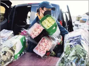  ?? Jessica Christian / The Chronicle ?? Courtney Sayner of The Floral Loft in San Francisco loads a cart full of flowers into her car after shopping at the San Francisco Flower Market in San Francisco, Calif., on Thursday. The flower industry was among the hardest hit by the coronaviru­s pandemic last year. As the Bay Area continues to reopen, the San Francisco Flower Market has seen a boom in business leading up to Mother’s Day, the industry’s busiest day of the year.