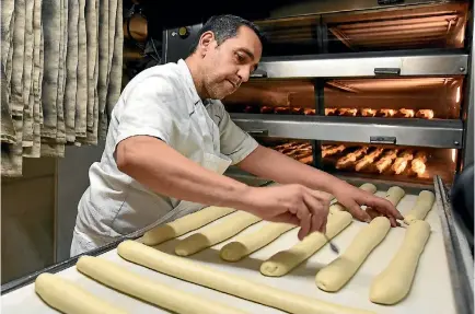  ?? PHOTO: GETTY IMAGES ?? Paris’ best baguette baker of Paris 2017 winner Sami Bouattour prepares traditiona­l French baguette for French President Emmanuel Macron who says baguettes are a cultural treasure.