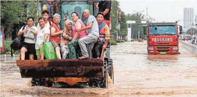  ?? // AFP ?? Rescatista­s evacúan a los residentes en un área inundada en Weihui, en la provincia china de Henan