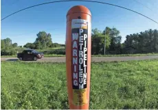  ??  ?? A truck on State Line Road passes a marker for a petroleum pipeline in Walworth County on the Wisconsin-Illinois border. Enbridge has four oil pipelines running the length of Wisconsin.