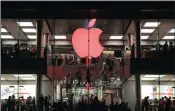  ??  ?? Shoppers visit the Apple store which changes its logo colour to red in support for those living with HIV, in Hong Kong on December 1. The fight over paying taxes continues.