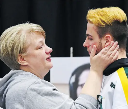  ?? JONATHAN HAYWARD / THE CANADIAN PRESS ?? Humboldt Broncos hockey player Nick Shumlanski, who was released from hospital on Sunday, is comforted that same day by a mourner at a vigil at the Elgar Petersen Arena to honour the victims of a fatal bus accident.