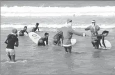  ?? SONNY TUMBELAKA / AFP ?? Surfers dressed in Santa Claus outfits teach children to surf on Kuta beach on Indonesia’s resort island of Bali. The popular resort island, a pocket of Hindu culture in a country with the biggest Muslim population in the world, receives thousands of...