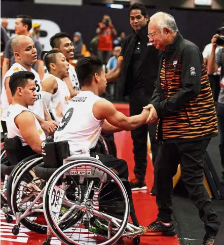  ??  ?? Moral support: Najib congratula­ting the players after their match against Thaland while Khairy looks on.