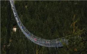  ?? ?? Visitors cross a suspension bridge for pedestrian­s that is the longest such constructi­on in the world after its official opening at a mountain resort in Dolni Morava, Czech Republic