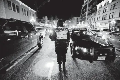  ??  ?? A Victoria police officer conducts a road check on Yates Street. A letter-writer suggests that Victoria needs more police officers than its population would normally require because it is a core municipali­ty in a much larger region.