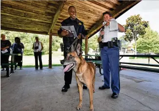  ?? HYOSUB SHIN / HSHIN@AJC.COM ?? Major L.J. Roscoe (right) of the DeKalb County Sheriff’s Office presents a retirement card to Viper and his partner and handler, Deputy Sheriff Michael McRae, on Tuesday.