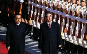  ?? AP/ANDY WONG ?? Chinese Premier Li Keqiang (left) and Japanese Prime Minister Shinzo Abe review an honor guard Friday during a welcome ceremony for Abe at the Great Hall of the People in Beijing.