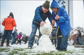  ?? MARTIN BERNETTI / AFP ?? People make a snowman in Santiago, Chile, on Saturday. An unusual snowfall surprised the inhabitant­s of the Chilean capital, causing power cuts and traffic jams.