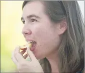  ??  ?? Wheatland resident Katie Farinha tastes a peach from KT Farm & Produce during the 20th annual Peach Festival in Marysville.