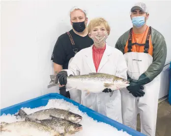  ?? AQUABOUNTY TECHNOLOGI­ES ?? CEO Sylvia Wulf holds geneticall­y modified salmon from the company’s indoor aquacultur­e farm May 26 in Albany, Indiana. With Wulf are processing associates Skyler Miller, left, and Jacob Clawson. The fish grow twice as fast as wild salmon.