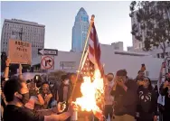  ??  ?? A man burns an upsidedown US flag at a protest in Los Angeles on Wednesday. — AFP