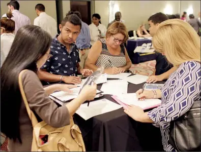  ?? AP/LYNNE SLADKY ?? Job seekers fill out applicatio­ns at a career event in July in Miami Lakes, Fla. The low level of applicatio­ns for jobless benefits suggests employers likely are looking to add workers, analysts say.