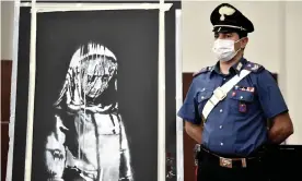  ?? Photograph: Filippo Monteforte/AFP/Getty Images ?? A member of Italy’s carabinier­i stands alongside the mural after it was found in the Abruzzo region east of Rome.