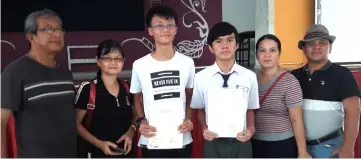  ??  ?? Liong (left) and Emmanuel show their results certificat­e together with their respective parents.