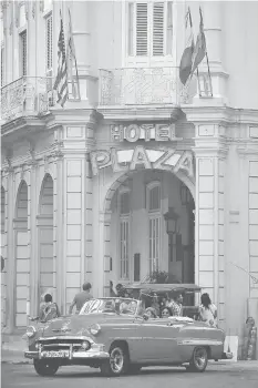  ??  ?? An Old American car drives past the Plaza Hotel in Havana.