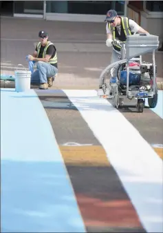  ?? Herald photo by Tijana Martin ?? Jeff Game, left, and Chad Zaremba paint the world's first city council-approved transgende­r flag city crosswalk along 3 Avenue and 6 Street South on Thursday. @TMartinHer­ald