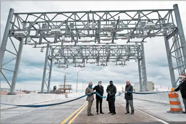  ?? KYLE TELECHAN/POST-TRIBUNE PHOTOS ?? Officials cut a ribbon under an overhead gantry on Cline Avenue Bridge during a grand opening ceremony for the roadway on Wednesday. The road almost didn’t happen at all after the state shut it down in early 2009.