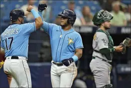  ?? Shea Langeliers. PHOTOS BY CHRIS O'MEARA — THE ASSOCIATED PRESS ?? Tampa Bay Rays' Harold Ramirez, center, celebrates his two-run home run off Oakland Athletics starting pitcher James Kaprielian with Isaac Paredes during the fifth inning of a baseball game Sunday, April 9, 2023, in St. Petersburg, Fla. Catching for Oakland is