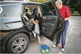  ??  ?? Marvin Speer helps his great grandchild­ren into the car after their preschool.